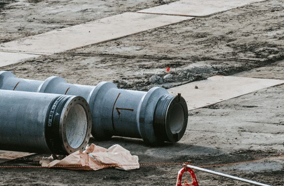 Construction site with large pipes that are waiting to be installed while implementing soil stabilization and void filling solutions to reinforce foundations and prevent erosion damage.