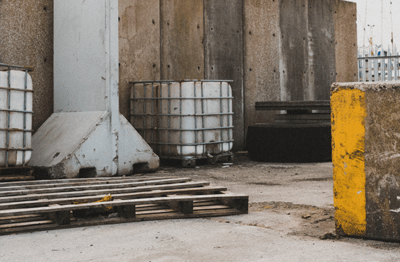 Exterior view of a commercial warehouse with uneven soil that needs to be stabilized for industrial use.